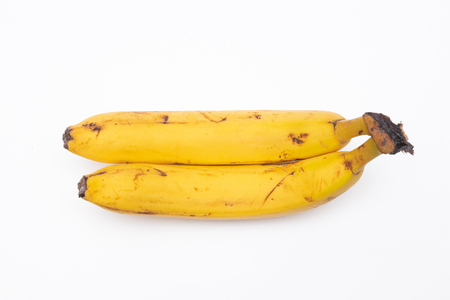 A pair of ripe bananas on an isolated white background. The two bananas are overripe, and attached at the stem.の写真素材