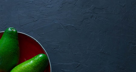 whole avocado lies on a handmade plate. The concept of healthy eating fruits and vegetables. view from above. space for text. copy spaceの写真素材