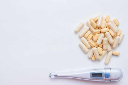 Medical thermometer, pills and capsules with the drug. Top view on white background with place for text. free space. antibiotics from the disease.の写真素材