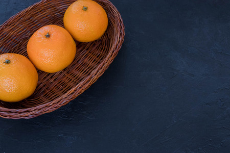 Tangerines in a basket, Christmas decor on a dark background. The concept of holidays. View from...