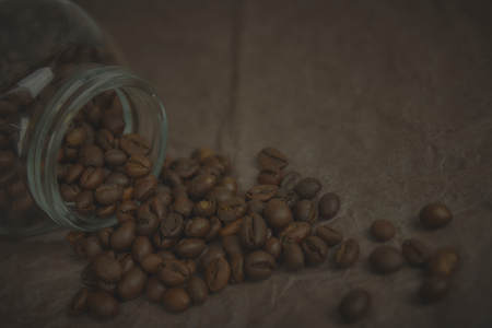 A pile of coffee beans spilling out of a can on coffee-colored paper, horizontal view.の写真素材