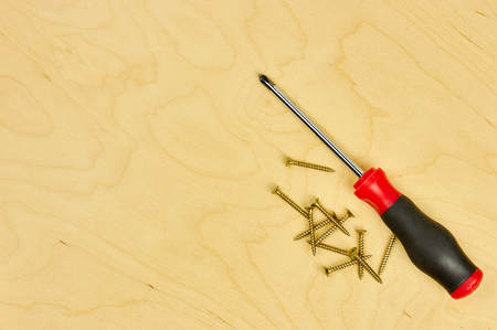 screwdriver and pliers with screws lie on the plywood. DIY concept.の写真素材