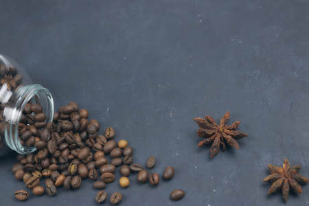 roasted coffee beans poured from a glass jar. angular placement of the coffee object. on dark concrete. horizontal view. copy spaceの写真素材