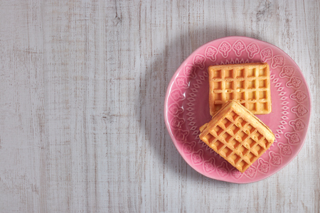Top view sweet fresh Viennese waffles on plate isolated on wooden table. copy space. pastries for breakfast.の写真素材