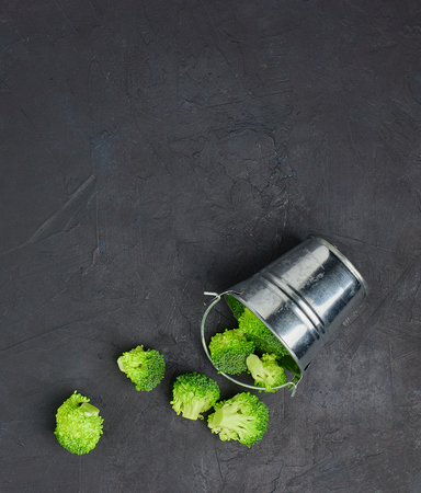 placer green broccoli segments from a small bucket. Healthy eating pattern on dark background. Copy space Top view. Vegetarian food.の写真素材