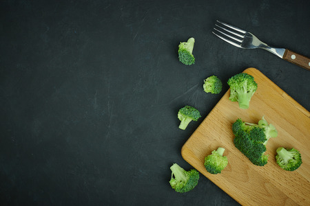 placer green broccoli segments from a small bucket. Healthy eating pattern on dark background. Copy space Top view. Vegetarian food.の写真素材