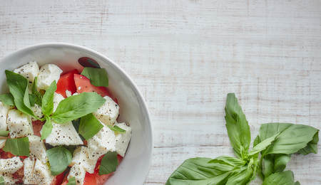 Greek salad with fresh vegetables on a wooden background, feta cheese and basil. Love for healthy...