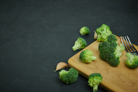 placer green broccoli segments from a small bucket. Healthy eating pattern on dark background. Copy space Top view. Vegetarian food.の写真素材