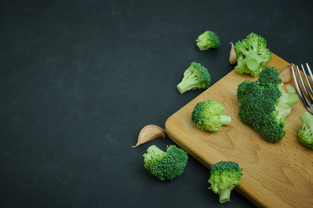 placer green broccoli segments from a small bucket. Healthy eating pattern on dark background. Copy space Top view. Vegetarian food.の写真素材
