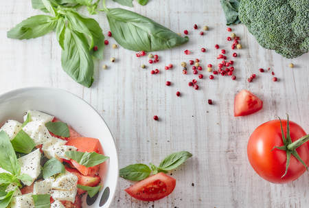 Greek salad with fresh vegetables on a wooden background, feta cheese and basil. Love for healthy raw food concept.の写真素材