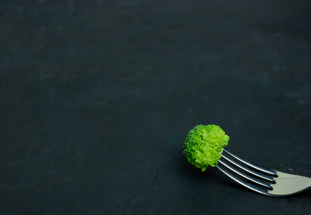 Fresh green broccoli cabbage lies on a fork. Template of healthy food on a dark background. Copy space Top view. Vegetarian food. view from above.の写真素材