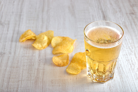 a glass of cold, light beer with chips scattered on the table. copy space. the view from the top. minimalismの写真素材