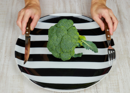 the concept of healthy. dietary food. green, raw broccoli lying on a plate, women's hands with devices. the view from the top. healthy diet. green cabbage close-up. HLS.vegetarian food. eating raw food. HLS.の写真素材