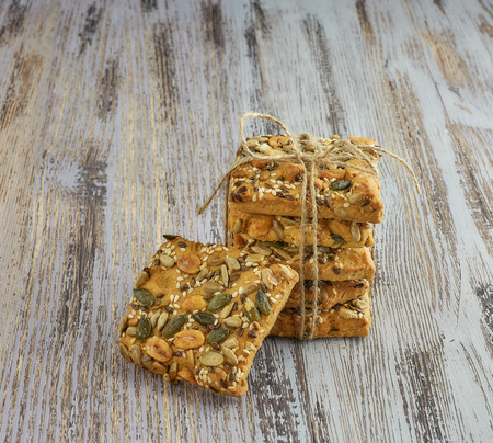 A stack of shortbread cookies with different types of nuts to a delicious coffee or tea on a dark wood table. horizontal view.の写真素材