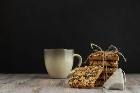 A stack of shortbread cookies with different types of nuts to a delicious coffee or tea on a dark wood table. horizontal view.の写真素材