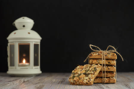 A stack of shortbread cookies with different types of nuts to a delicious coffee or tea on a dark...