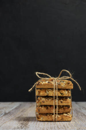 A stack of shortbread cookies with different types of nuts to a delicious coffee or tea on a dark...