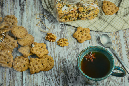 ceramic Cup of black tea with a handful of cookies with nuts on a white, old, shabby wooden table, vertical view. the composition of the morning Breakfast with cookies.の写真素材