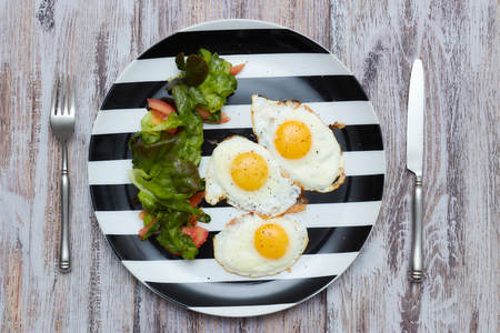 Morning healthy Breakfast. fried eggs with fresh lettuce and vegetables. plate on an old, light, shabby table with . Top viewの写真素材