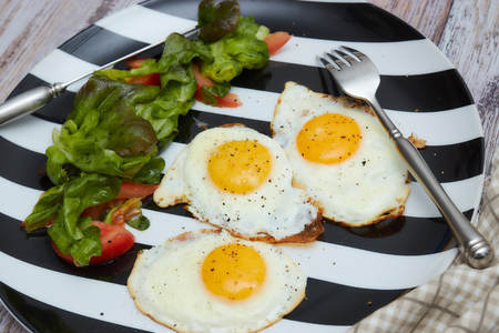 Morning healthy Breakfast. fried eggs with fresh lettuce and vegetables. plate on an old, light, shabby table with . Top viewの写真素材