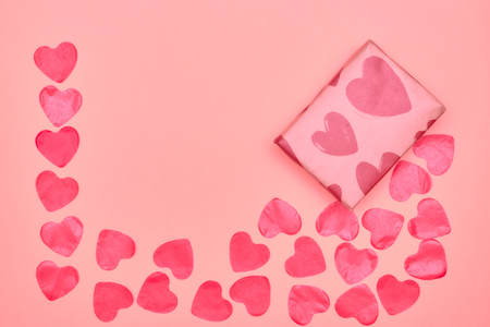 Gift in Kraft paper with red hearts on pink background with hearts. The Concept Of Valentine's Day.の写真素材