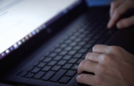 Woman working on laptop in home office hand on keyboard close up.の写真素材