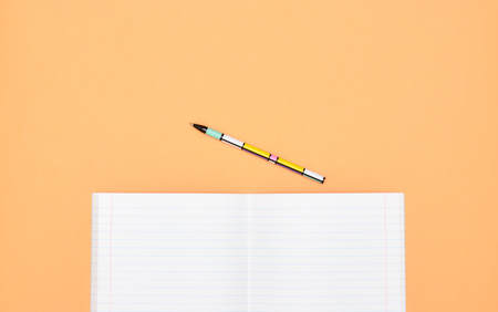 Notebook, pen and colored numbers on orange background. Accessories for study. Mathematics,, flat, copy spaceの写真素材
