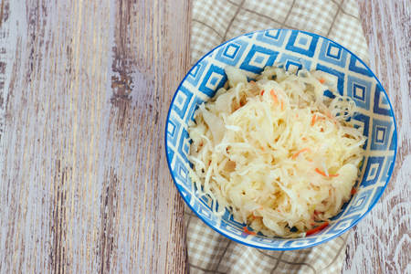 salad of pickled cabbage. Traditional Russian appetizer sauerkraut with carrots in a plate on a white wooden table. Rustic style. Selective focus and copy spaceの写真素材