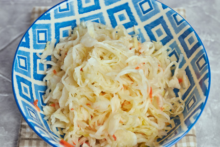 salad of pickled cabbage. Traditional Russian appetizer sauerkraut with carrots in a plate on a white wooden table. Rustic style. Selective focus and copy spaceの写真素材