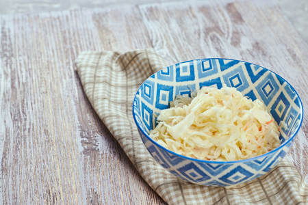 salad of pickled cabbage. Traditional Russian appetizer sauerkraut with carrots in a plate on a white wooden table. Rustic style. Selective focus and copy spaceの写真素材
