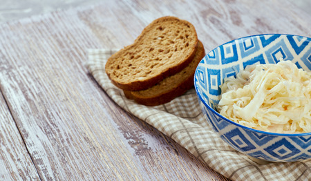 salad of pickled cabbage. Traditional Russian appetizer sauerkraut with carrots in a plate on a white wooden table. Rustic style. Selective focus and copy spaceの写真素材
