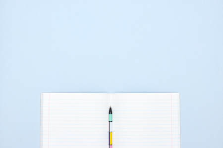 open school notebook with pen on blue background. a clean, white sheet of notebook paper for recording.の写真素材