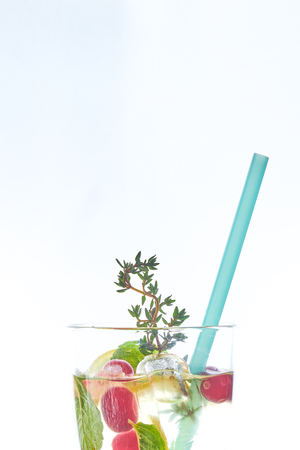 Cold mint berry cocktail in a sling isolated on white. copy space. summer refreshing drink with a straw.の写真素材