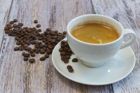 A Cup of fragrant black coffee and a handful of coffee beans on an old wooden table close-up. in the morning to drink.の写真素材