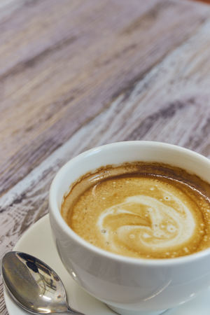 white Cup of coffee on a wooden table close-up. black coffee with milk. wooden table with a fragrantの写真素材