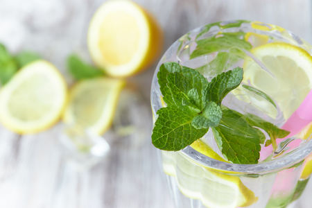 Lemonade with ice and fresh lemon with mint on wooden background. horizontal view. copy space. refreshing summer drink.の写真素材