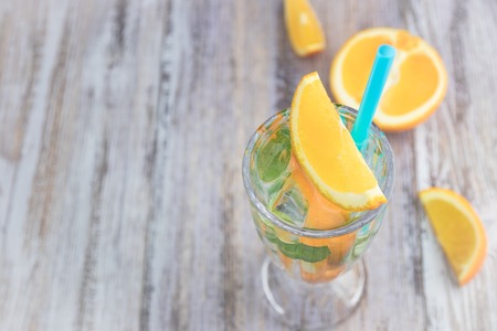 Citrus refreshing drink in a glass goblet on a wooden table. summer refreshing cocktail. Healthy food, drinks. orange and mint ice water. Copy space.の写真素材