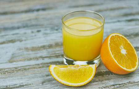 a glass of fresh orange juice with fresh citrus fruits on a light wooden table. horizontal view.の写真素材