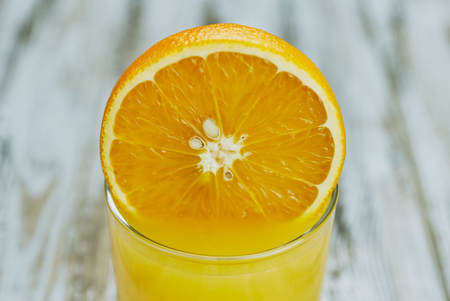 a glass of fresh orange juice with fresh citrus fruits on a light wooden table. horizontal view.