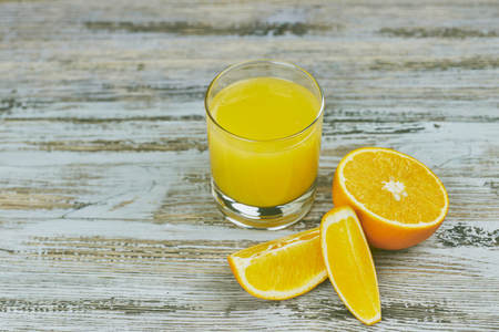 a glass of fresh orange juice with fresh citrus fruits on a light wooden table. horizontal view.の写真素材
