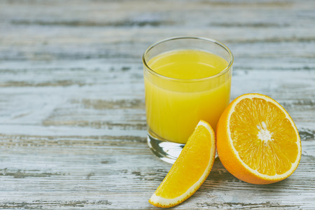 a glass of fresh orange juice with fresh citrus fruits on a light wooden table. horizontal view.の写真素材