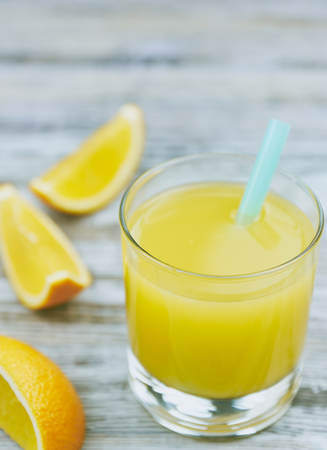 A glass of fresh orange juice and orange fruits on a wooden table. vertical view close-up. refreshingの写真素材