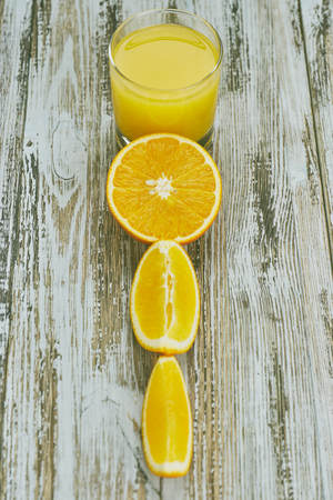 A glass of fresh orange juice and orange fruits on a wooden table. vertical view close-up. refreshingの写真素材