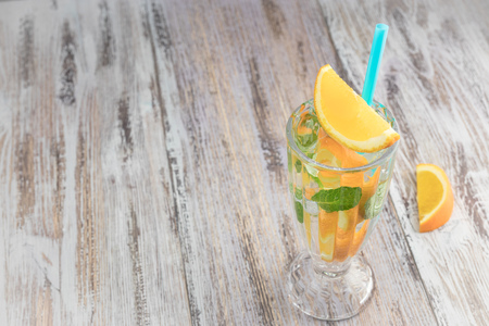 Citrus refreshing drink in a glass goblet on a wooden table. summer refreshing cocktail. Healthy food, drinks. orange and mint ice water. Copy space.の写真素材