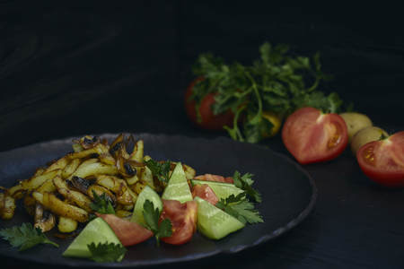 Freshly cooked fried potatoes with onions and mushrooms close-up on a plate. black wood table. horizontalの写真素材