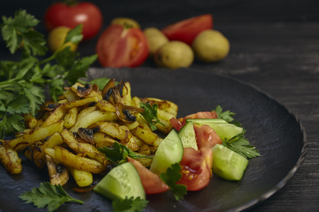 Freshly cooked fried potatoes with onions and mushrooms close-up on a plate. black wood table. horizontalの写真素材