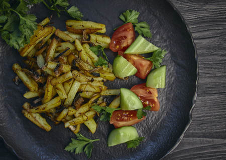 Freshly cooked fried potatoes with onions and mushrooms close-up on a plate. black wood table. horizontalの写真素材
