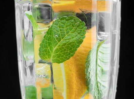 Glass with water, orange and mint. Close-up of a cocktail on a black background. citrus drink.の写真素材