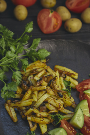 Freshly cooked fried potatoes with onions and mushrooms close-up on a plate. black wood table. horizontalの写真素材