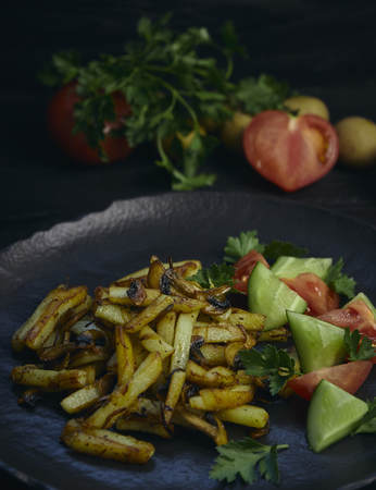 Freshly cooked fried potatoes with onions and mushrooms close-up on a plate. black wood table. horizontalの写真素材